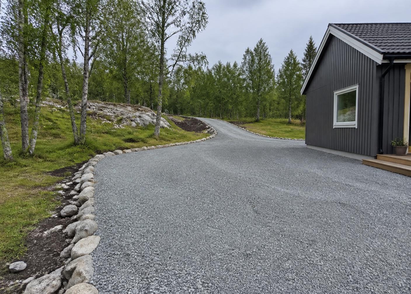 Illustrasjonsbilde: opparbeidet grusvei og gårdsplass med steinsatt kant ved en bolig.